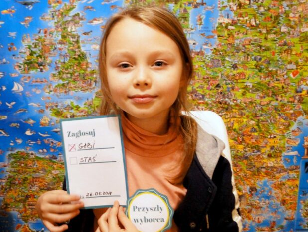 dziewczynka z listą do głosowania i znaczkiem małego wyborcy