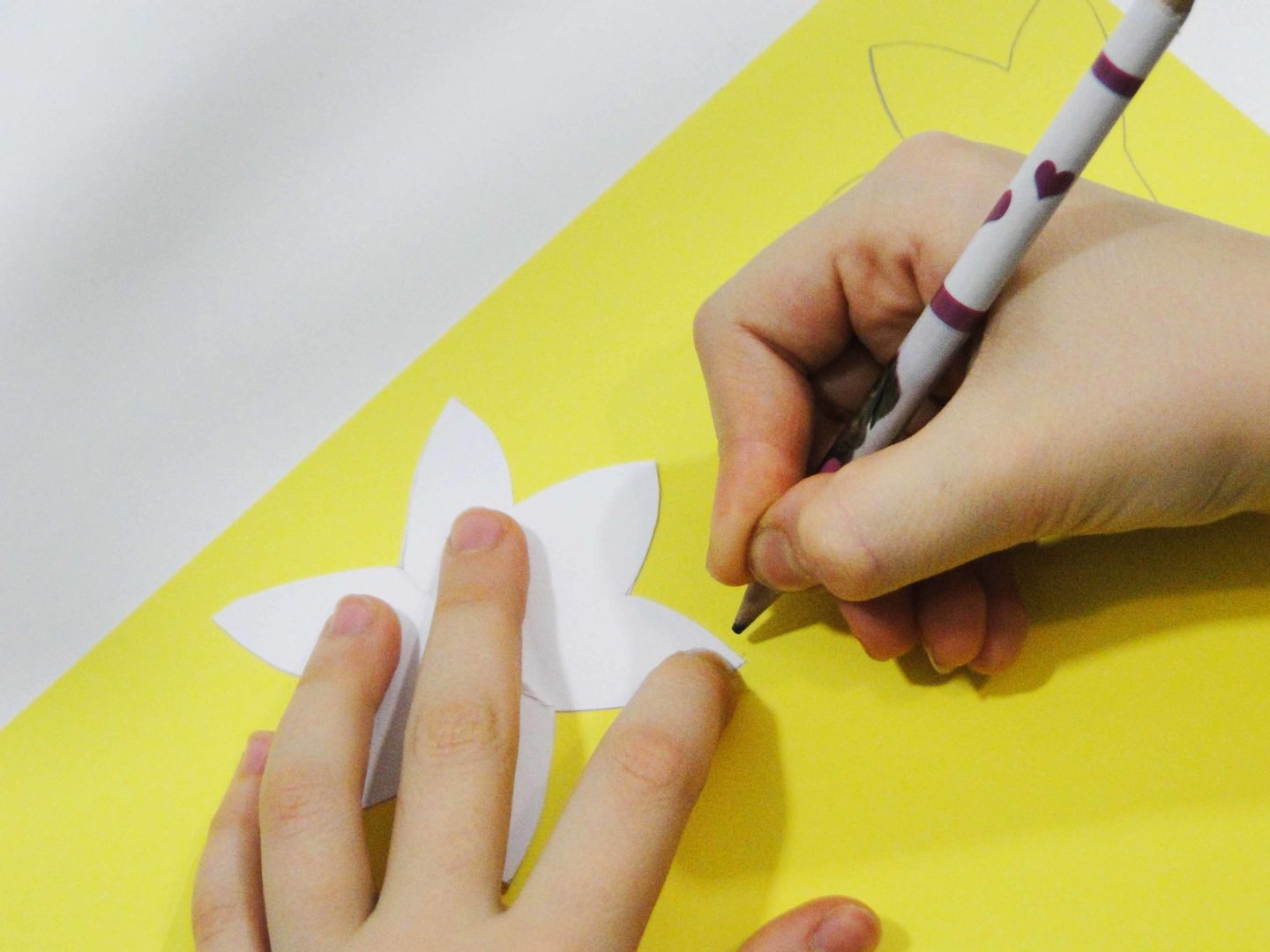 dziewczynka obrysowuje szablony na żółtym papierze