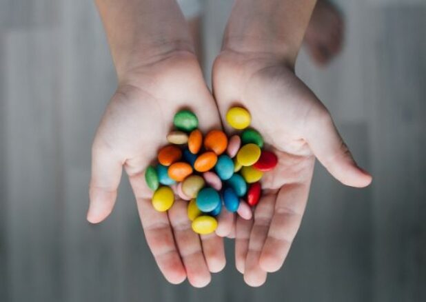 dłonie chłopak trzymające garść kolorowych cukierków