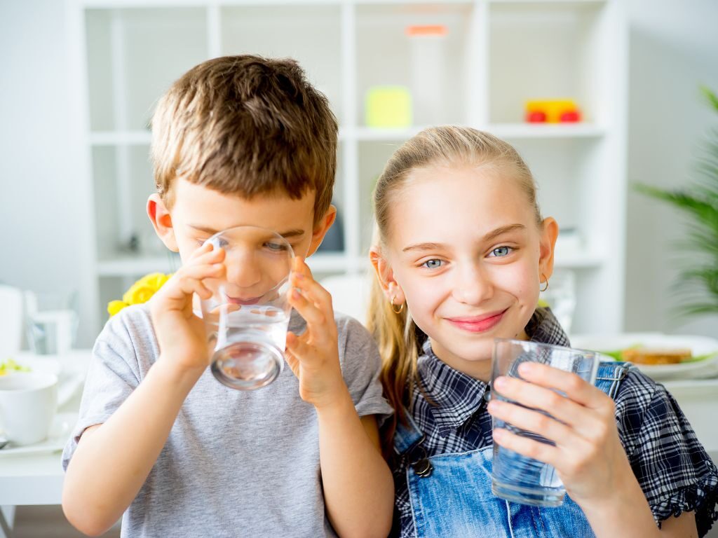 Chłopak i dziewczyna piją wodę ze szklanki.