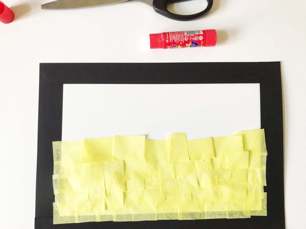 Fotografia przedstawia proces tworzenia witrażu z bibuły. Obok rozpoczętej pracy klej i nożyczki